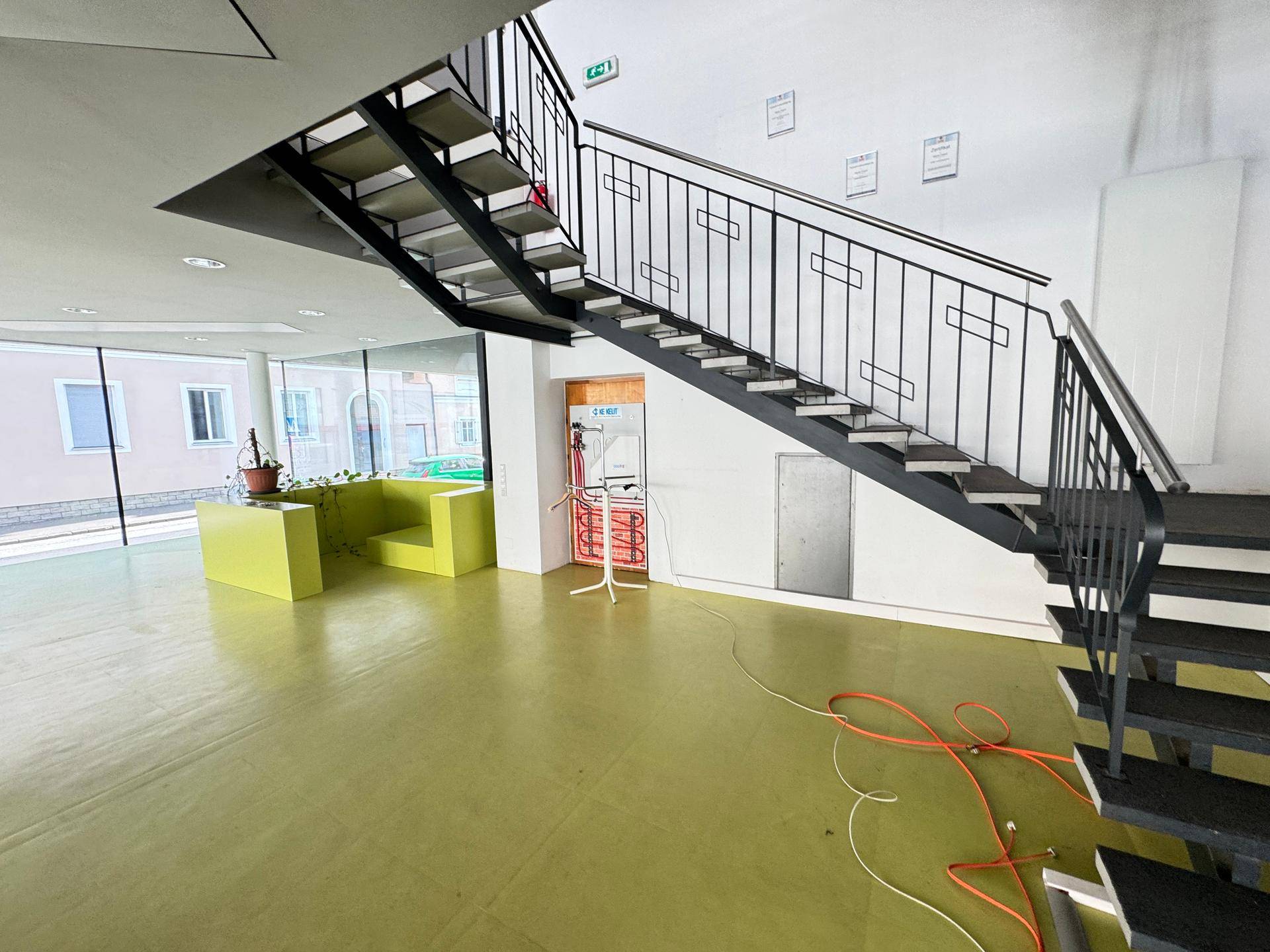 Offener Bereich mit Treppe und großen Fenstern, der viel Licht hereinlässt und eine moderne Atmosphäre schafft.