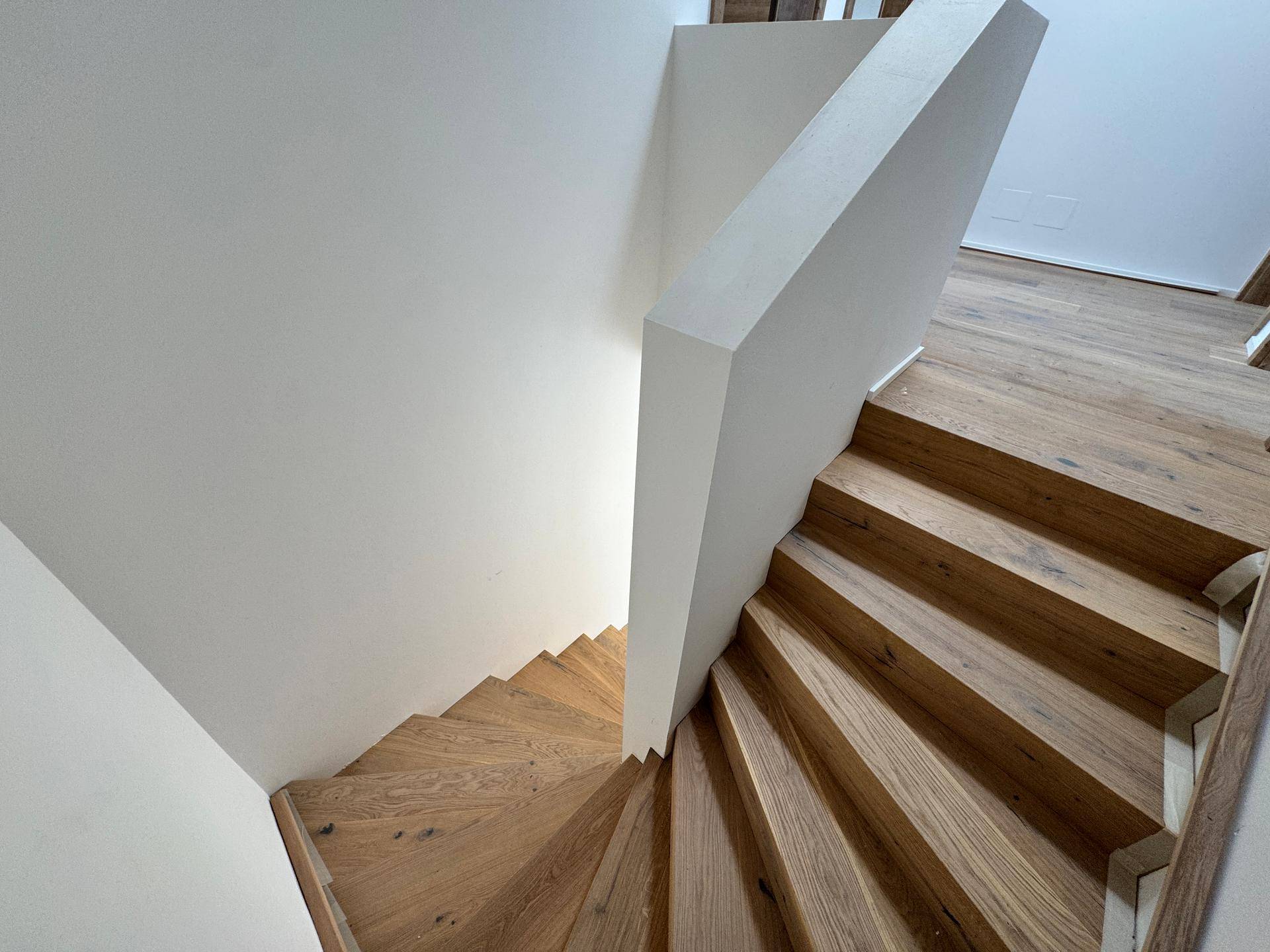 Detailansicht der modernen Holztreppe mit klaren Linien und weißem Treppenaufgang.