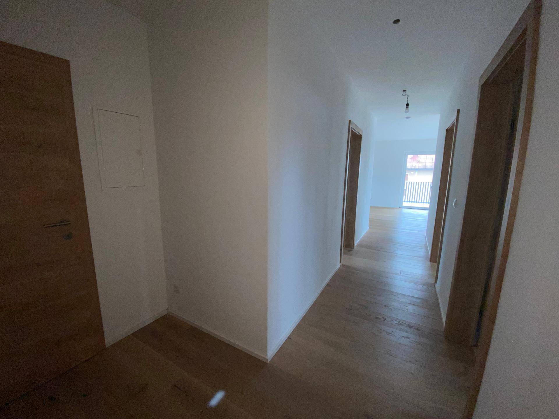 Heller Flur mit Holzboden und Holztüren, der zu den verschiedenen Räumen führt.
