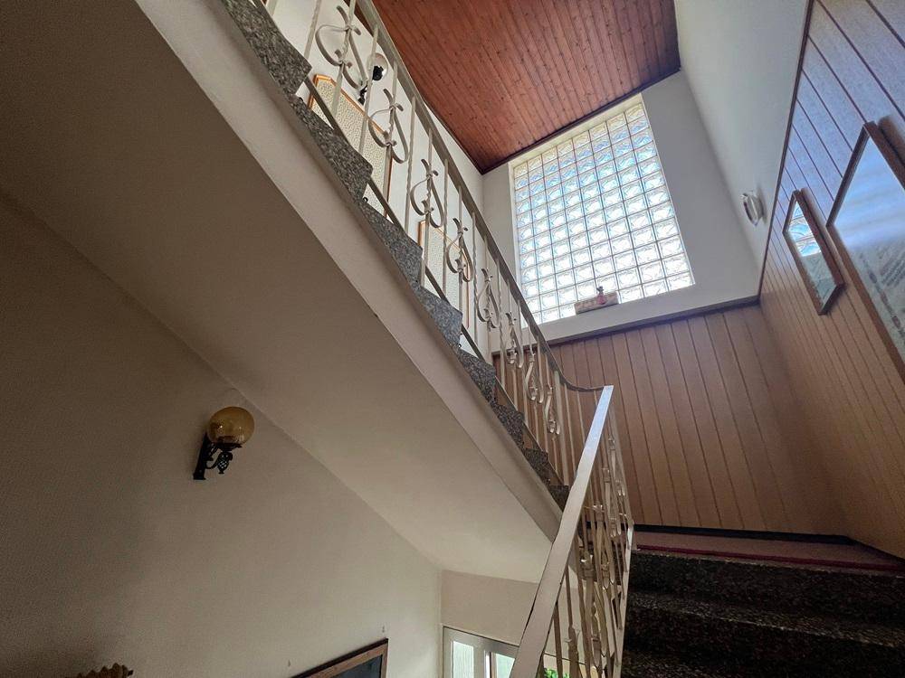 Treppenhaus mit Holzdecke, Glasbausteinfenster und einem Geländer im traditionellen Stil.