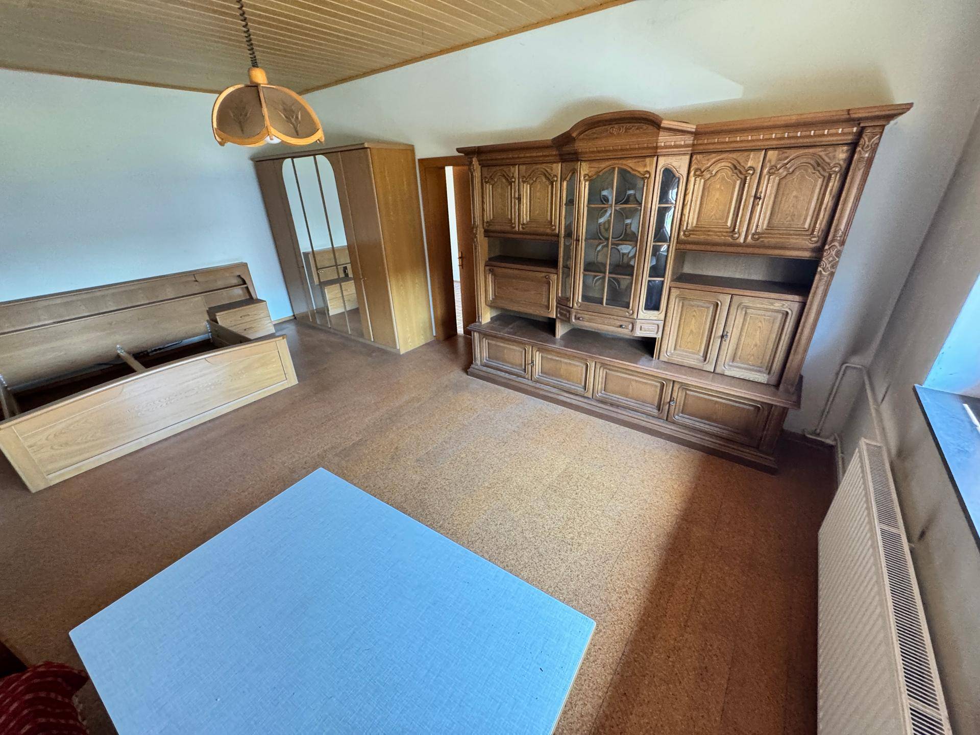 Schlafzimmer mit Holzdecke, Schrank und Blick auf den Außenbereich.