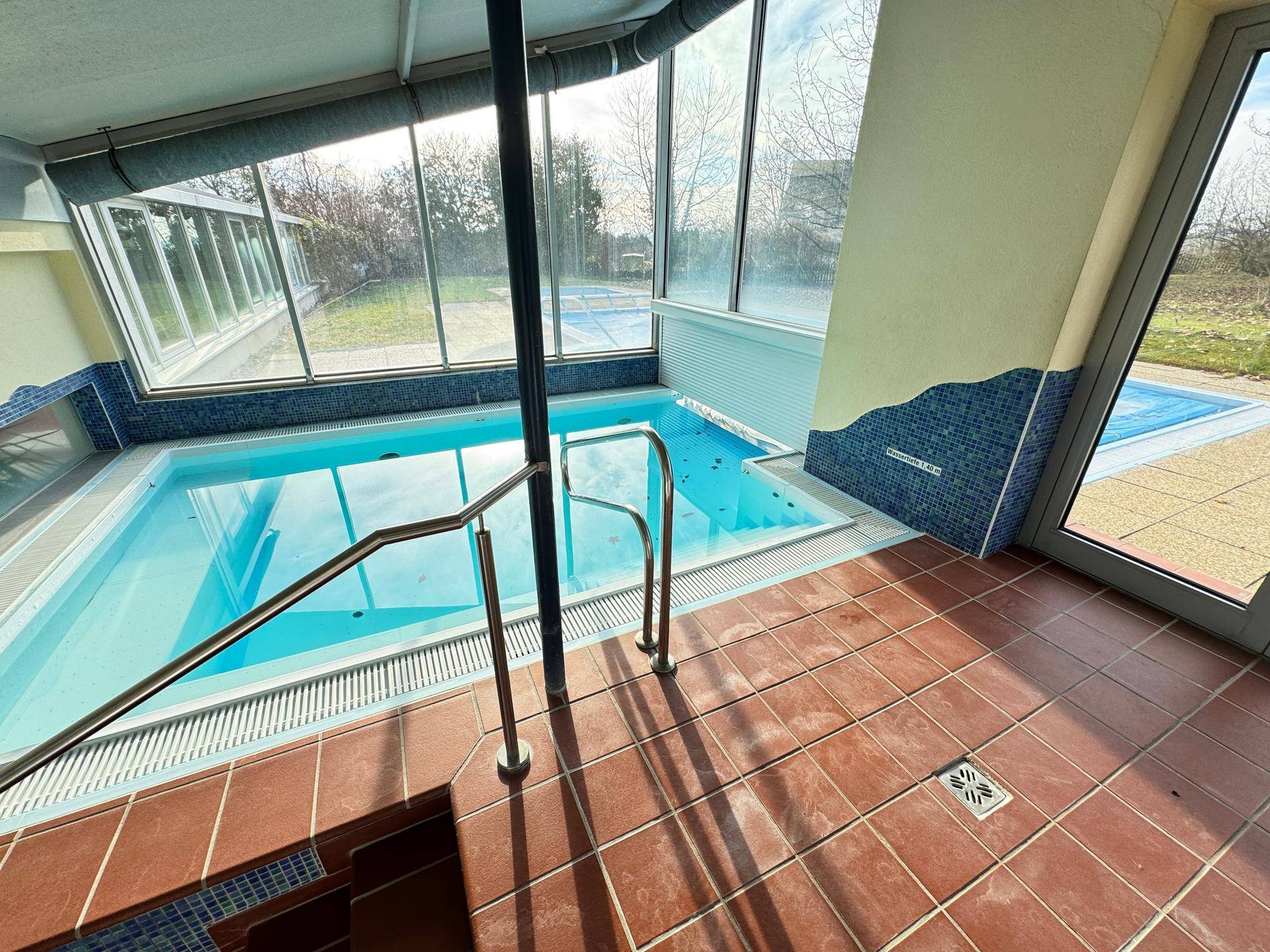 Innenpool mit Handlauf und Blick nach draußen durch große Fenster.