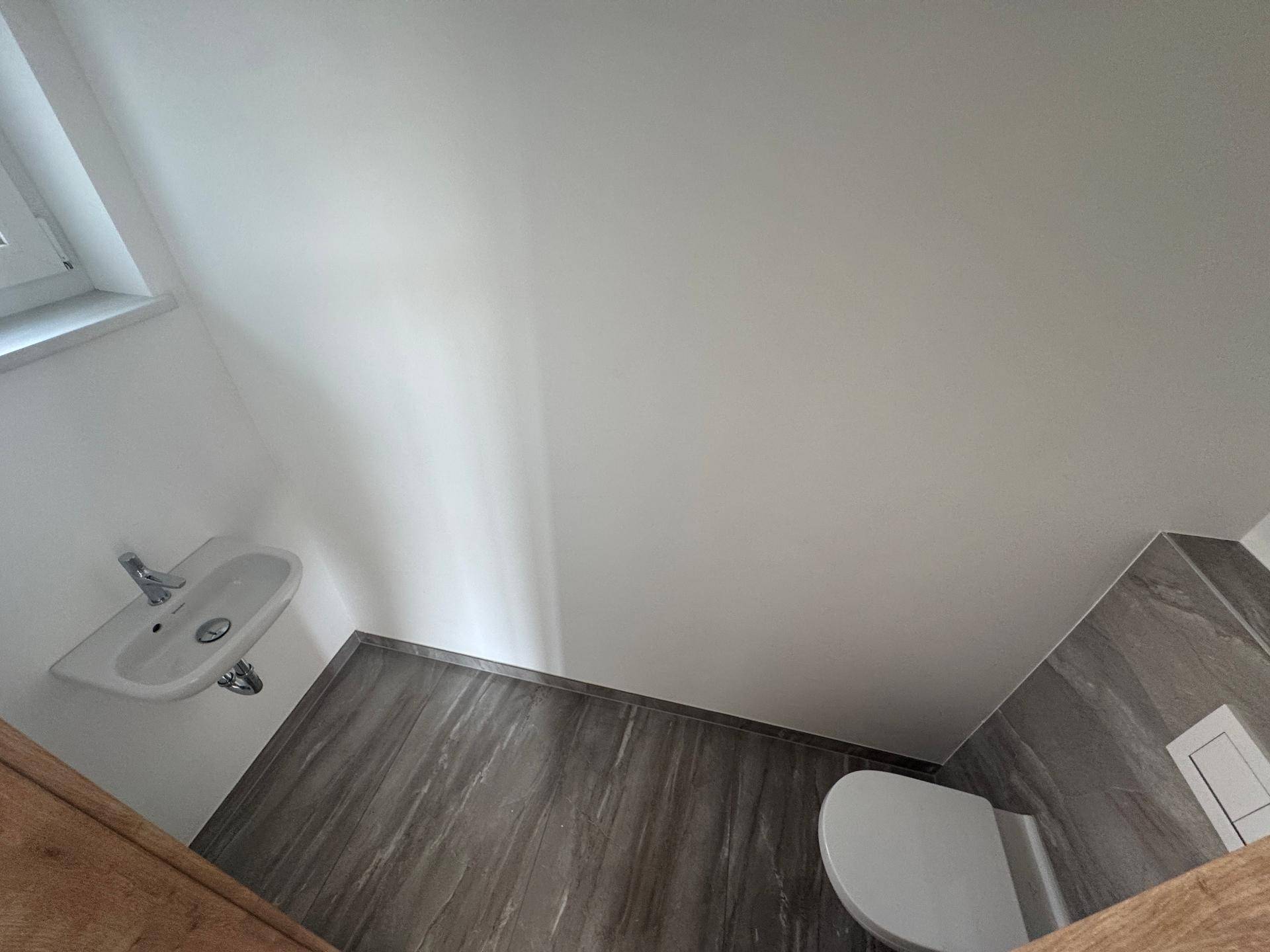Kleines Gäste-WC mit Waschbecken und Toilette, modern gefliest.