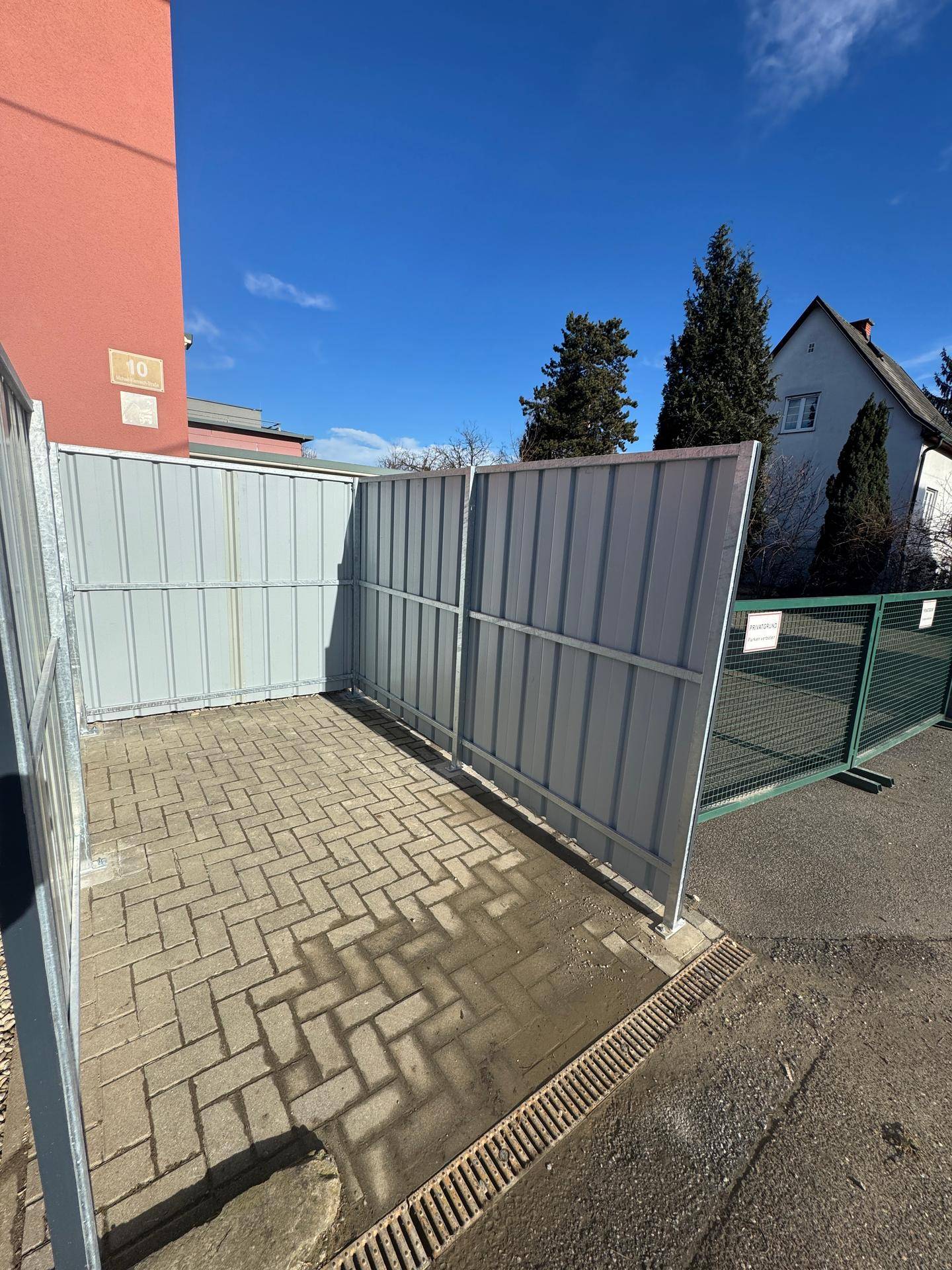 Abgegrenzter Außenbereich mit gepflastertem Boden, ideal als Stellplatz oder Lagerfläche.