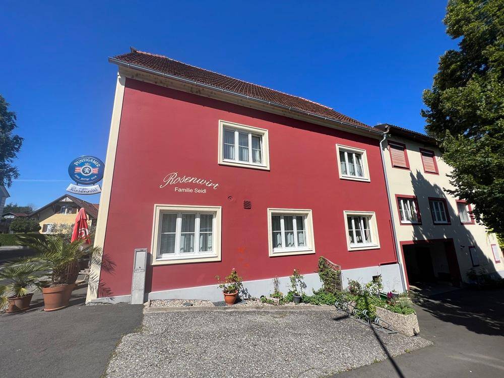Rotes Gebäude mit weißen Fenstern und einem Restaurant im Erdgeschoss, von der Seite gesehen.