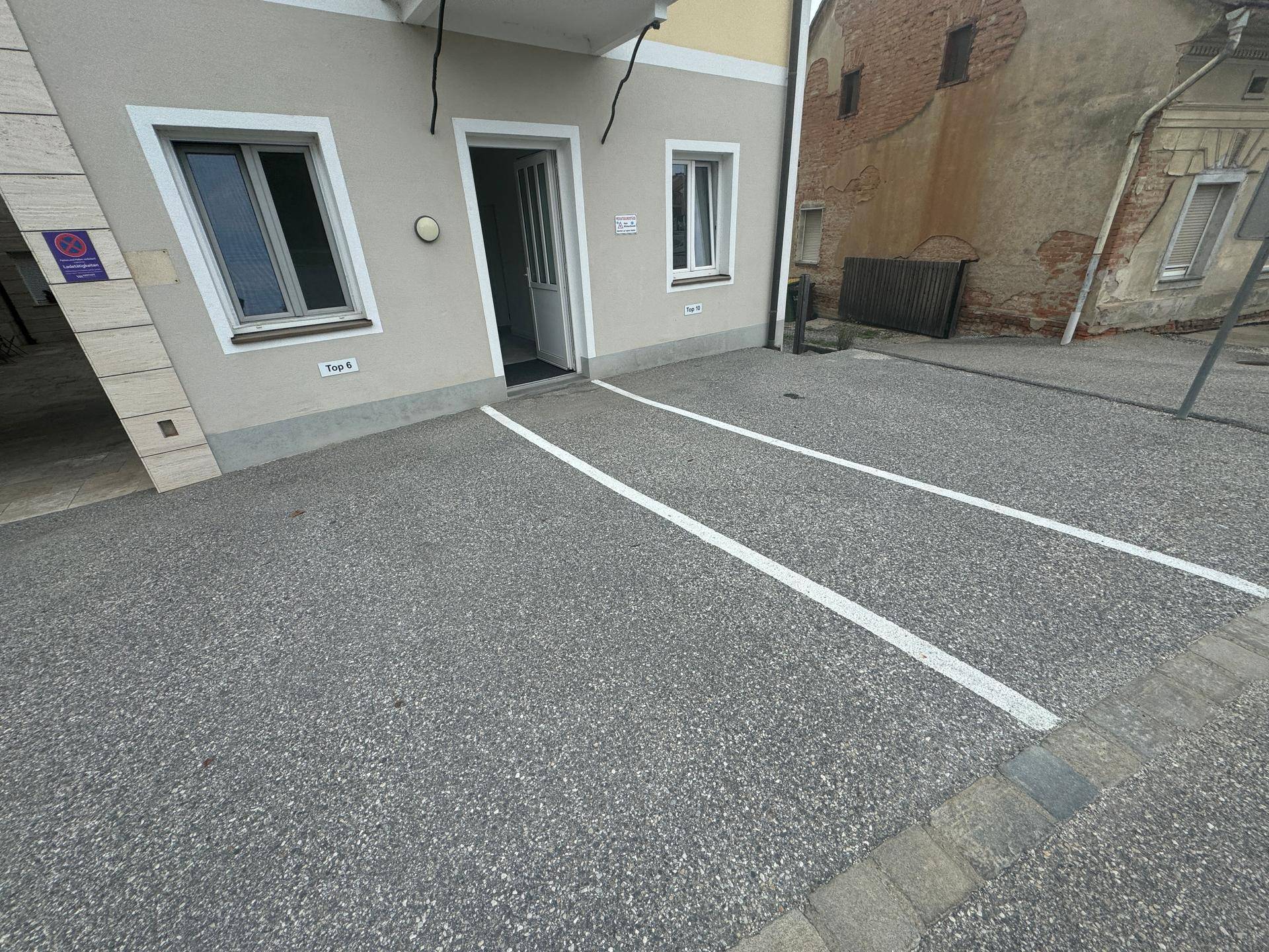 Außenbereich mit markierten Parkplätzen direkt vor dem Gebäudezugang, ideal für Bewohner und Besucher.