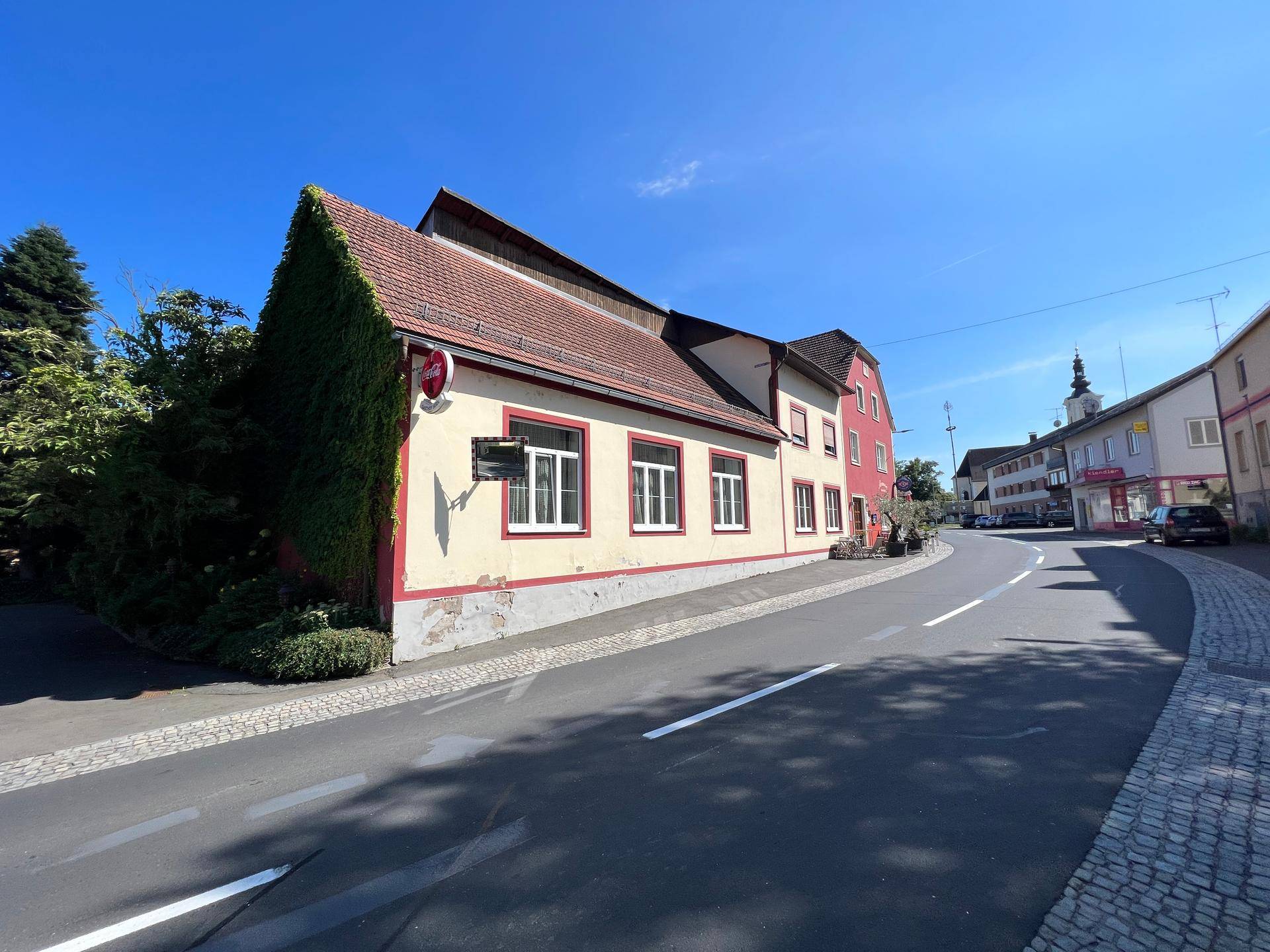 Gebäude an einer Straße mit begrüntem Giebel und blauem Himmel.
