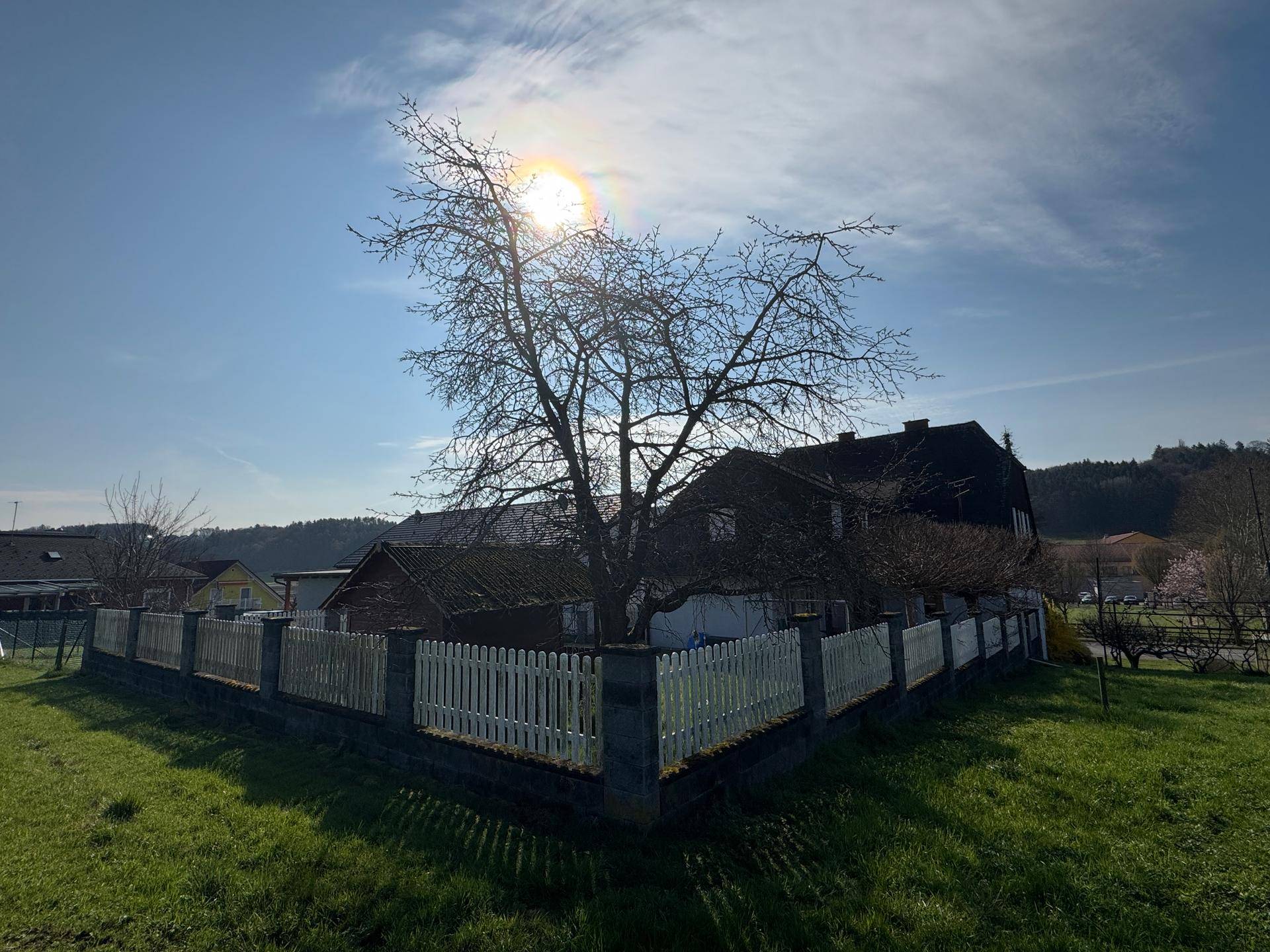 Panoramablick auf das Anwesen mit weiten Grünflächen und dem Haus unter blauem Himmel.