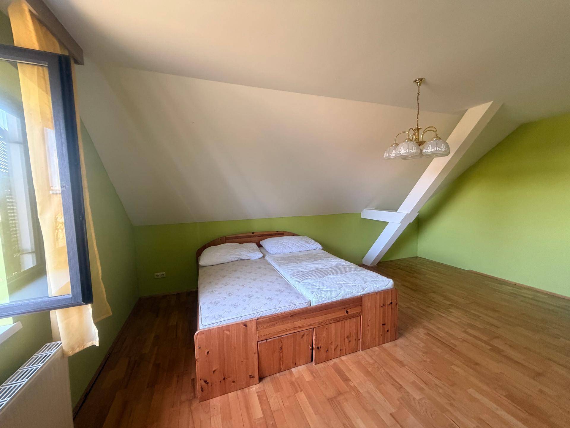 Helles Schlafzimmer im Dachgeschoss mit Holzboden und schrägen Wänden.