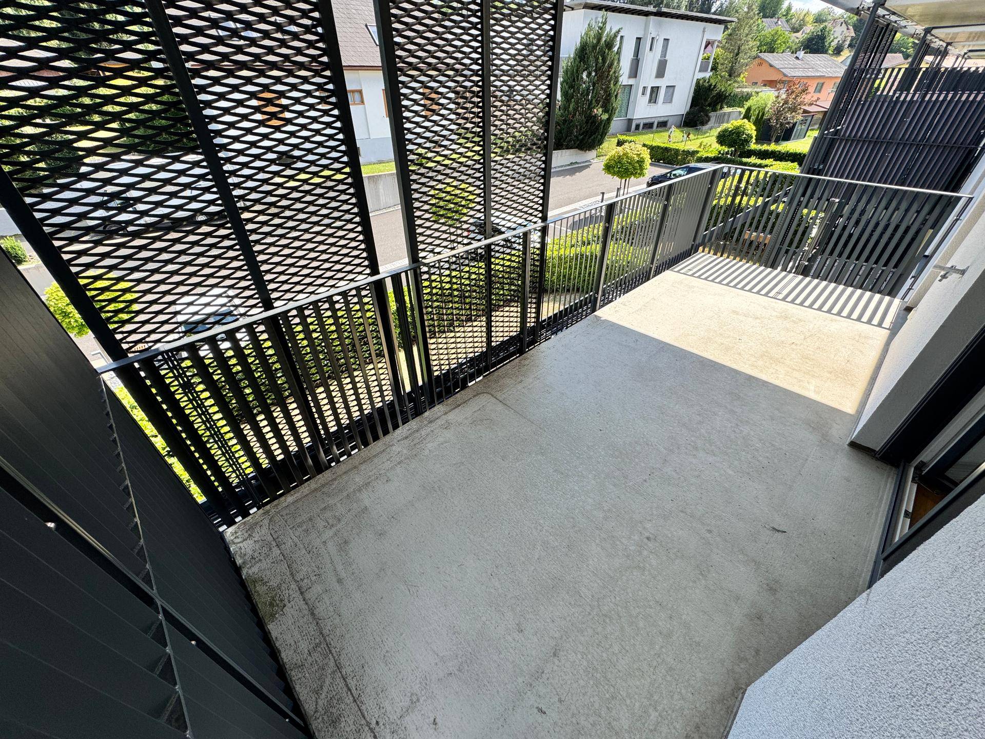 Großer Balkon mit schwarzem Metallgeländer und Blick auf die Umgebung, bietet viel Platz im Freien.