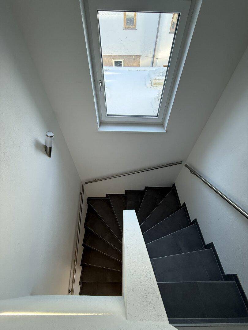 Heller Treppenaufgang mit Dachfenster, das viel natürliches Licht spendet und die Treppe beleuchtet.
