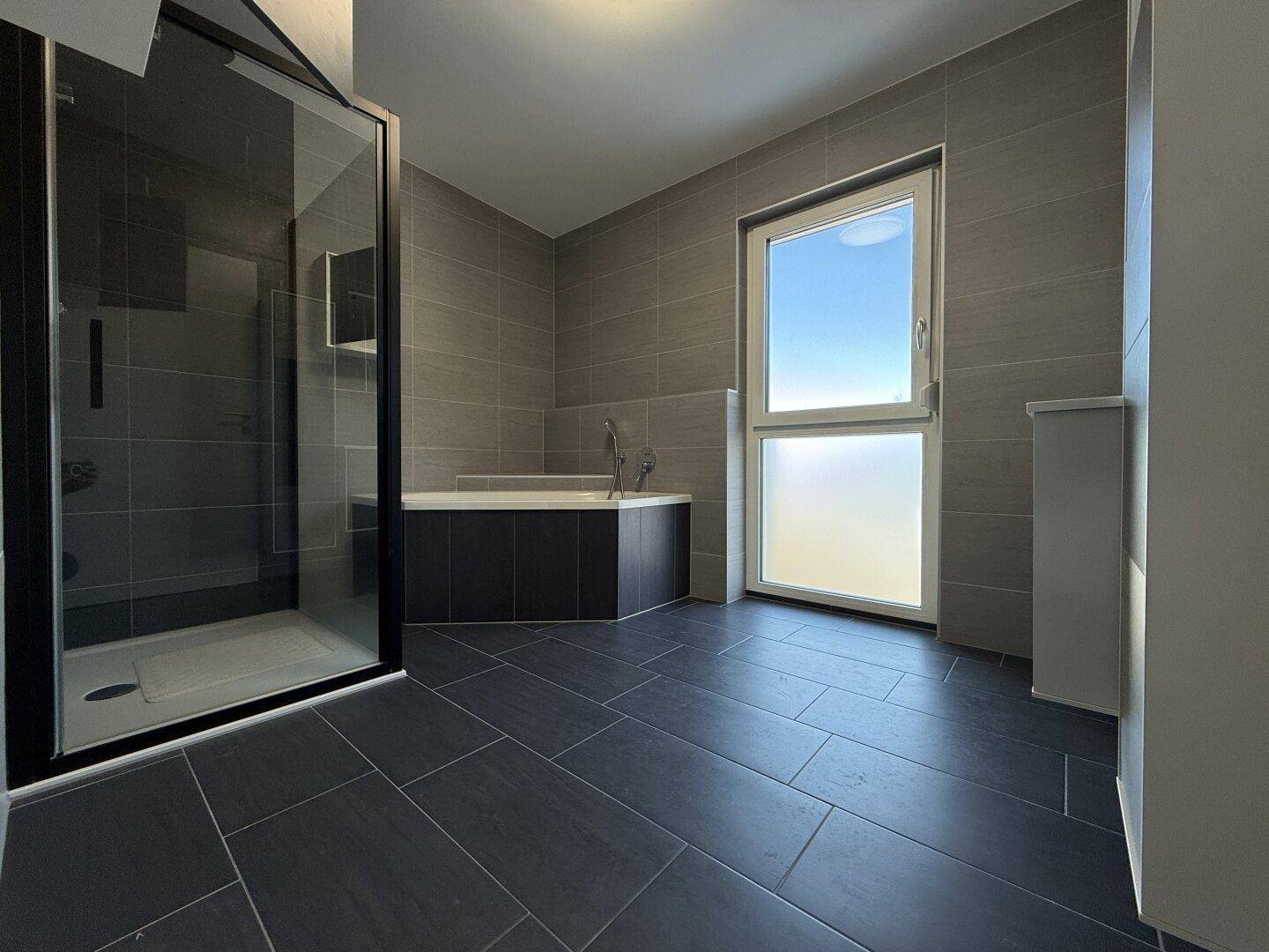 Geräumiges Badezimmer mit Eckbadewanne, Duschkabine und Fenster für natürliche Belüftung.