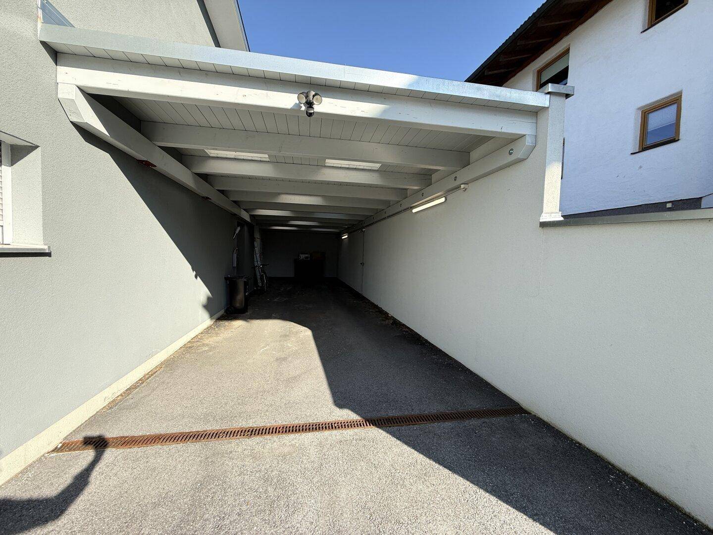 Überdachter Carport-Bereich mit Zufahrt, der Schutz für Fahrzeuge bietet.