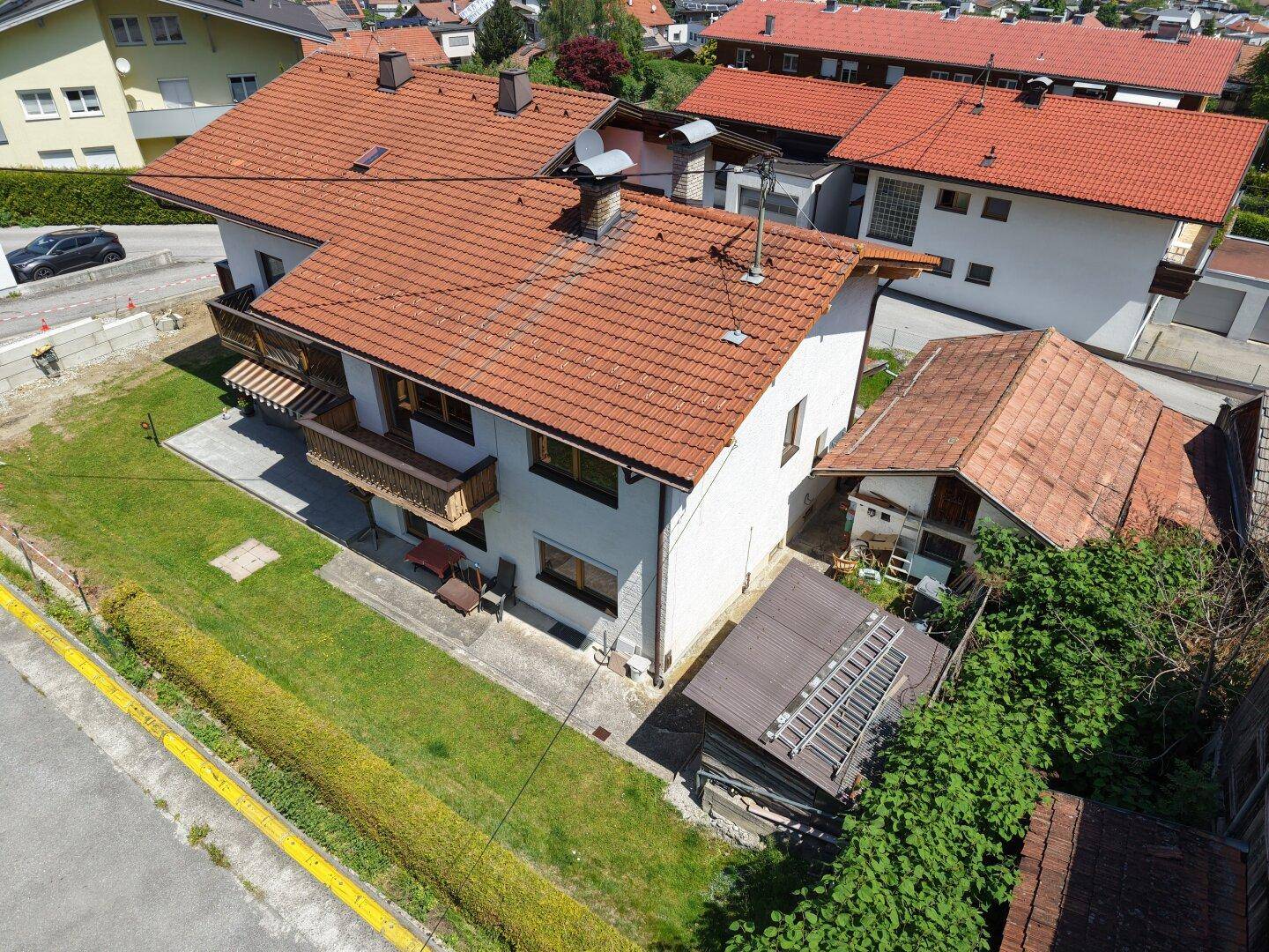 Vogelperspektive des Hauses mit Garten, Terrasse und angrenzendem Schuppenbereich.