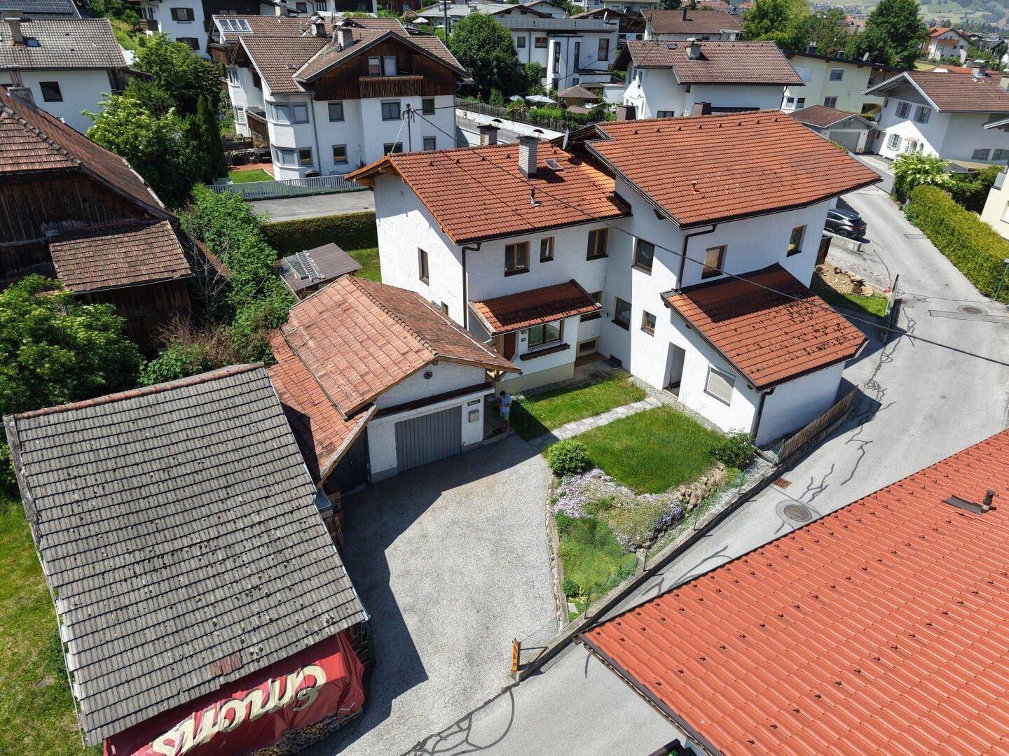 Luftaufnahme des Anwesens mit Hauptgebäude, Garage und umliegender Wohnbebauung.