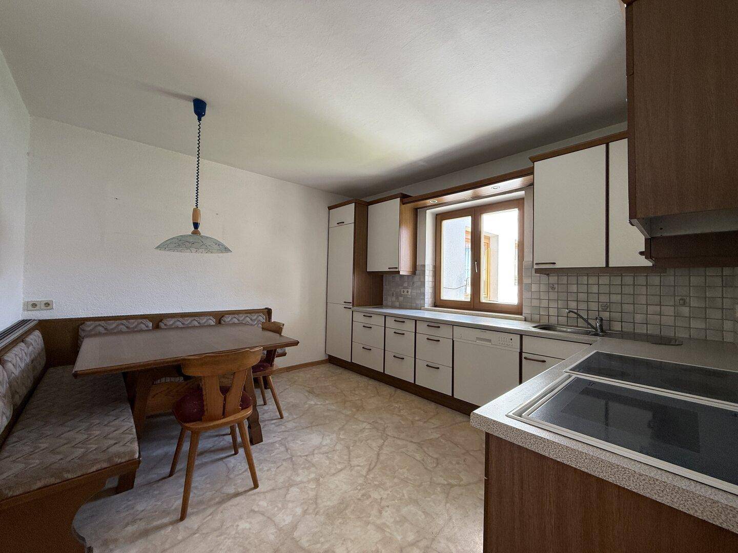 Traditionelle Küche mit Einbaumöbeln, Essbereich und Fenster mit Blick ins Grüne.