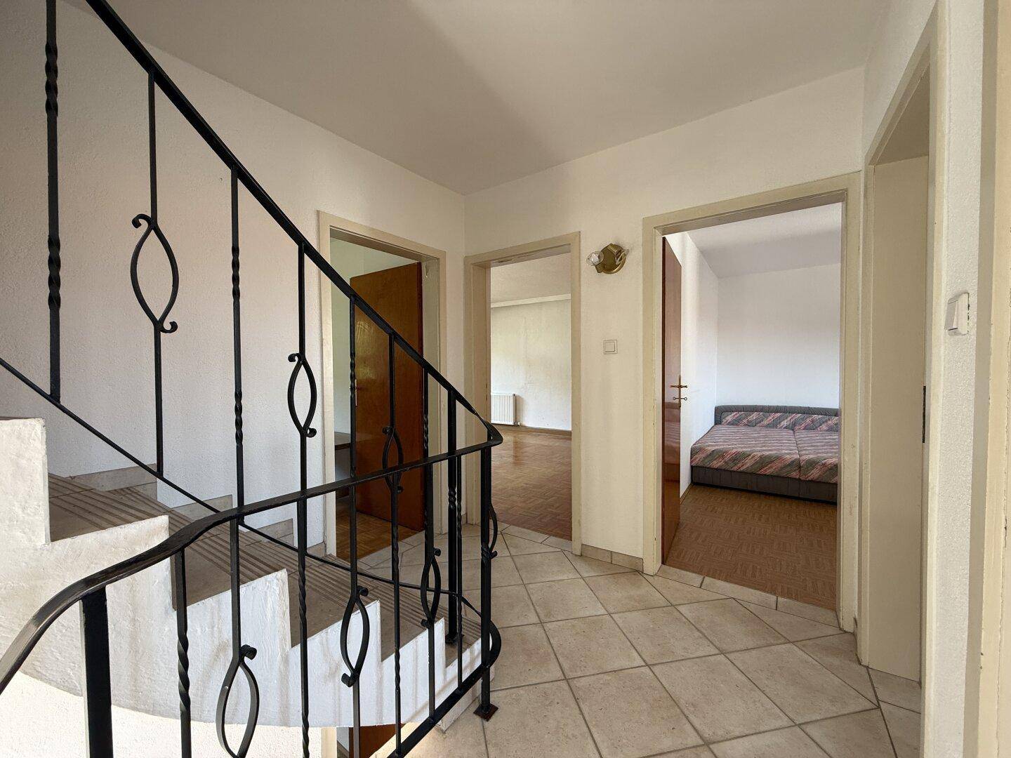 Heller Flur mit gefliestem Boden und Treppe zum Obergeschoss, angrenzend an weitere Zimmer.
