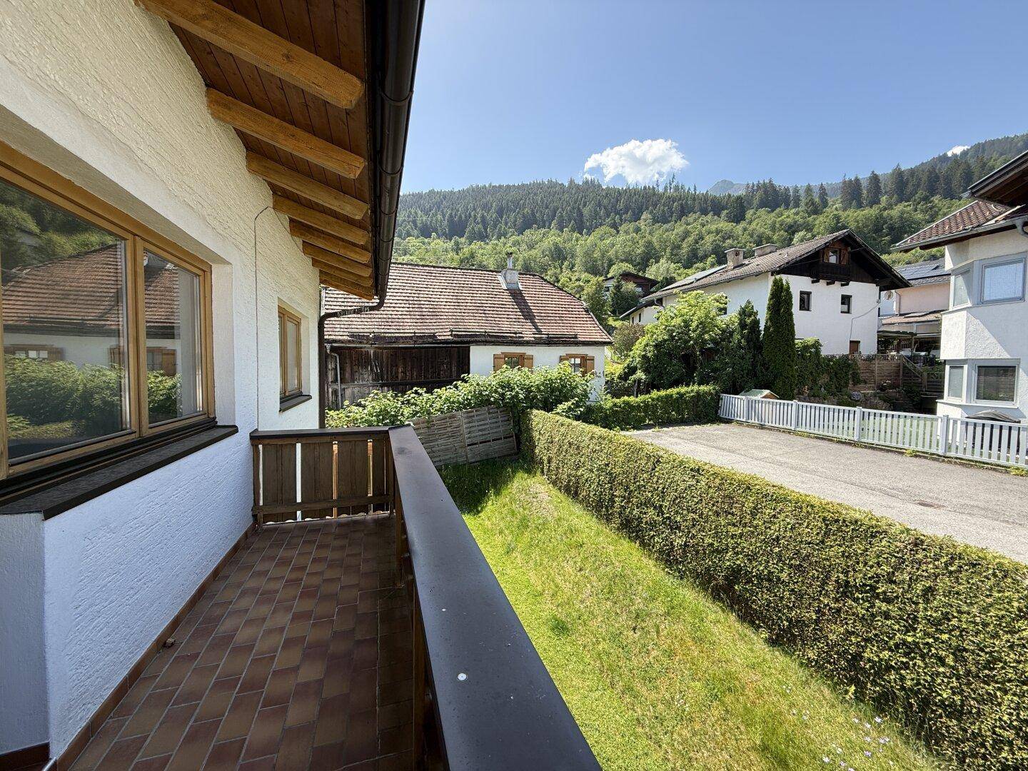 Balkon mit Holzboden und Geländer, bietet einen weiten Blick auf die grüne Umgebung.