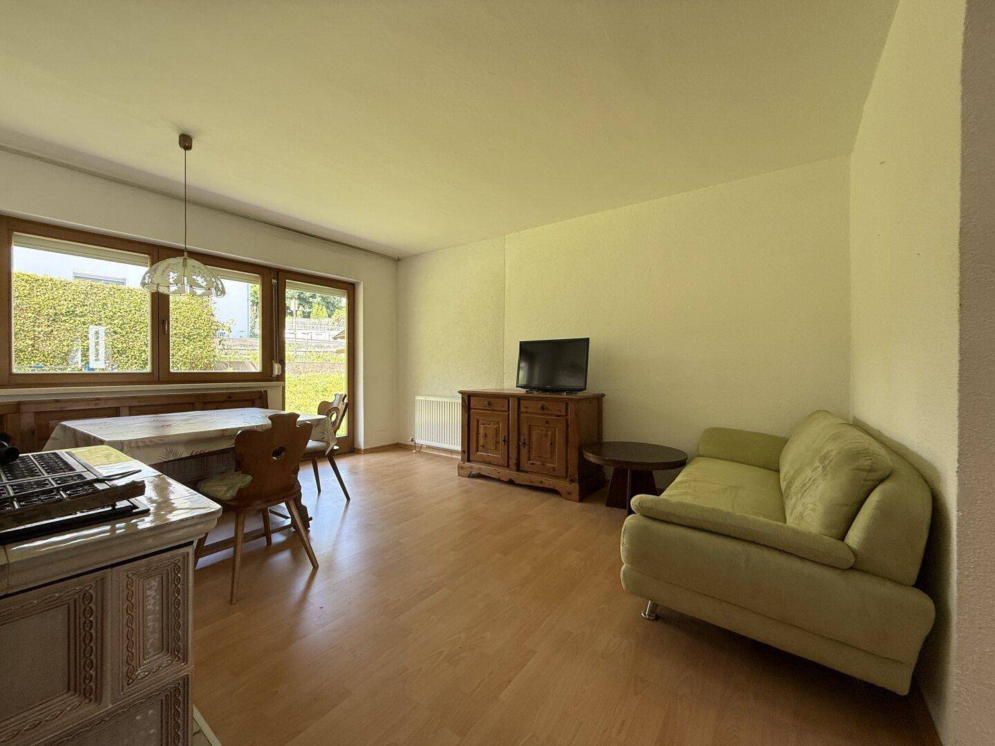 Wohnzimmer mit Holzboden, Esstisch und Blick auf den grünen Außenbereich.