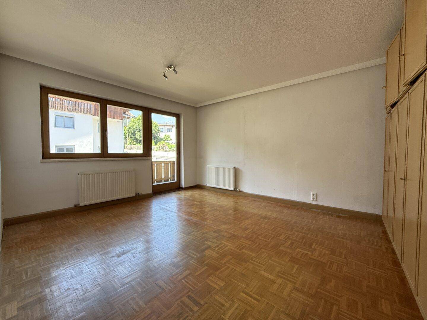 Geräumiges Schlafzimmer mit Parkettboden, Einbauschränken und Zugang zum Balkon.