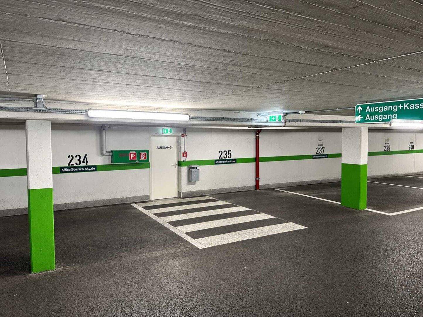 Tiefgarage mit markierten Parkplätzen, Betonwänden und Deckenbeleuchtung.