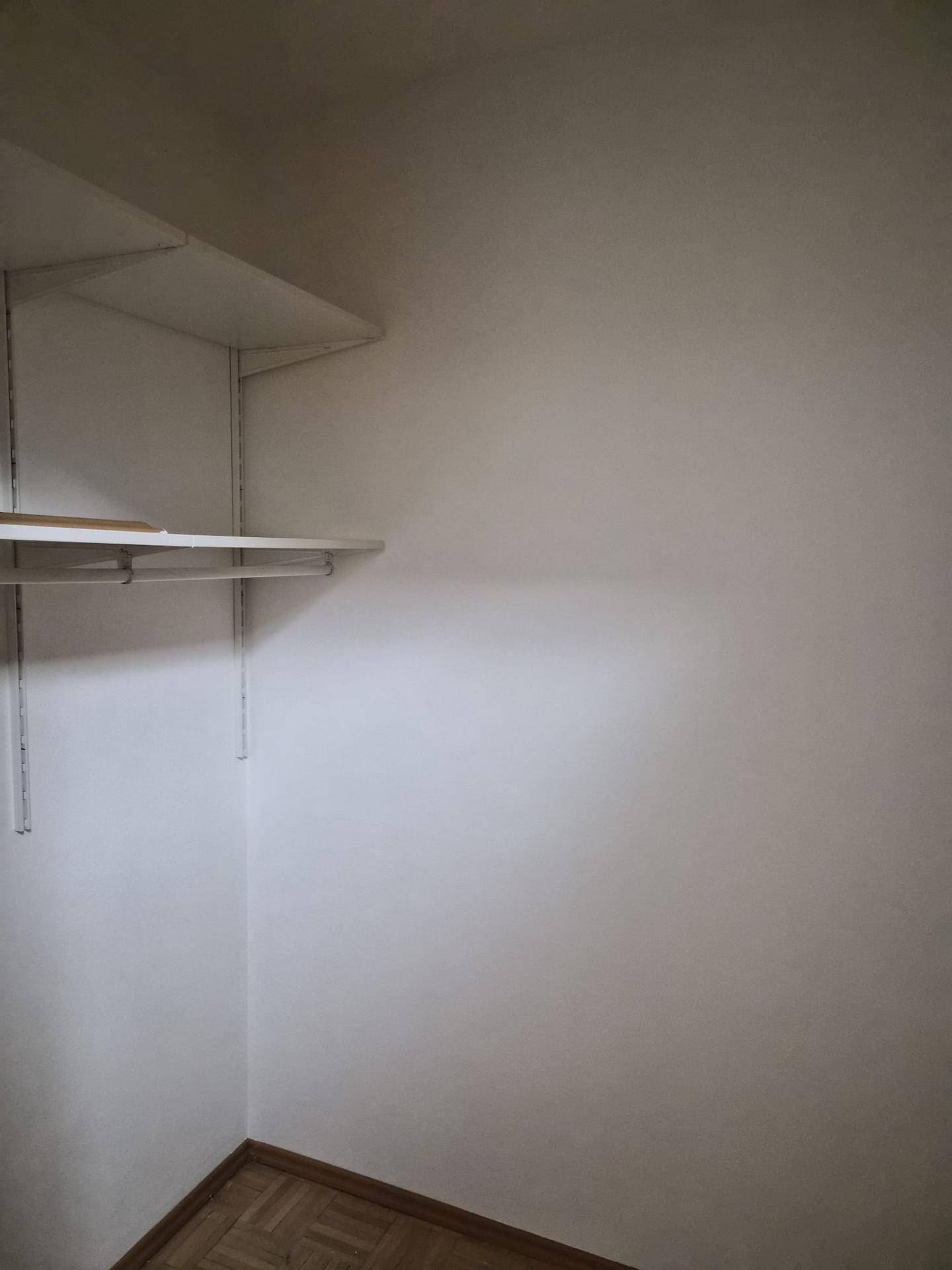 Kleiner Abstellraum mit praktischen Regalen und Kleiderstange für zusätzlichen Stauraum.