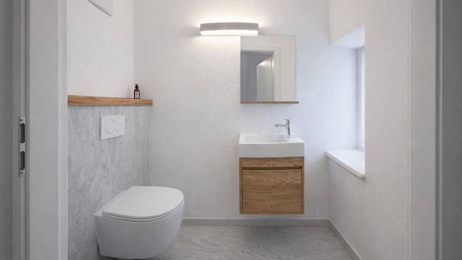 Helles Gäste-WC mit schwebendem Waschtisch, Wand-WC und Fenster für Tageslicht.