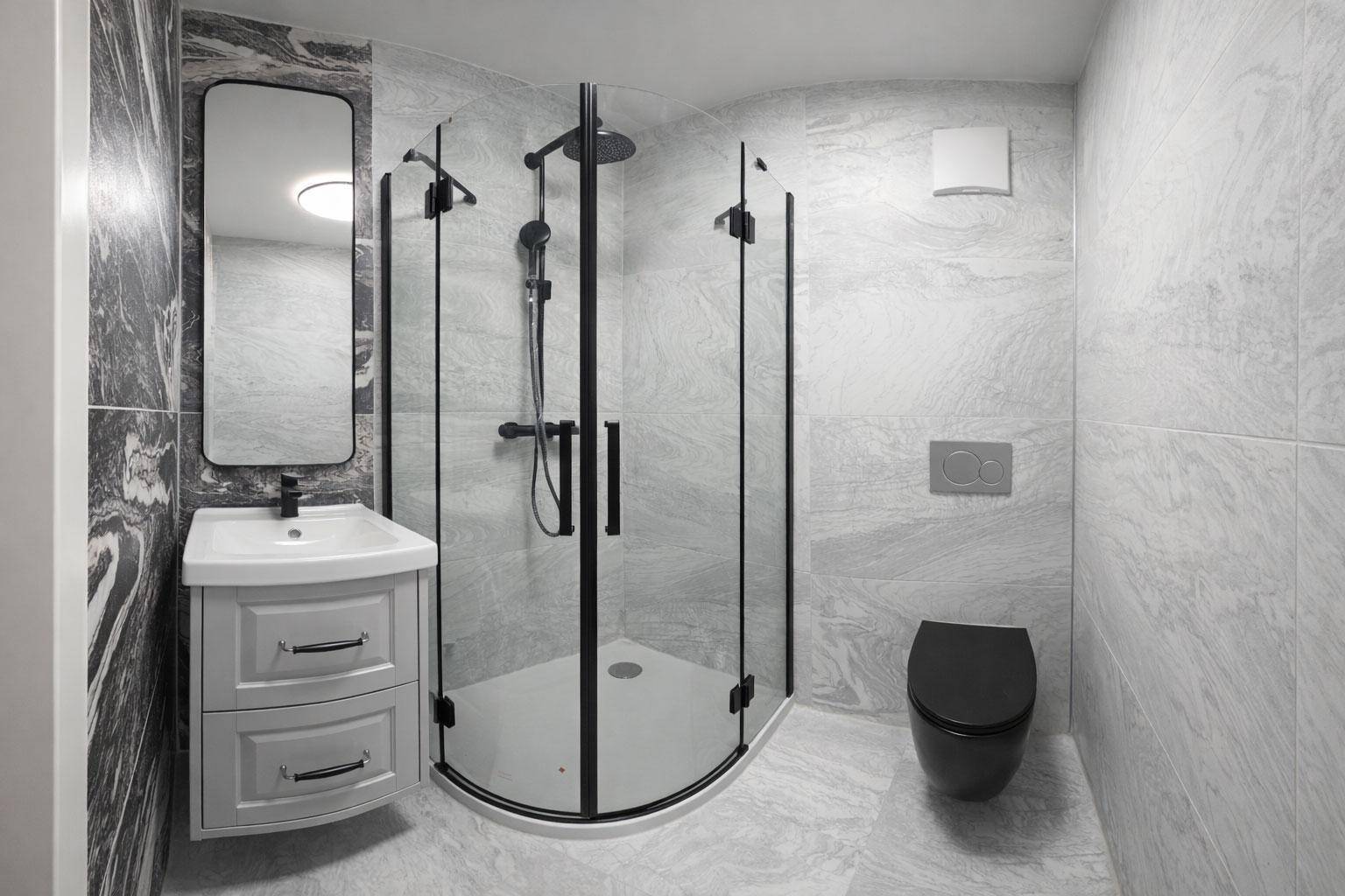 Modernes Badezimmer mit Eckdusche, schwarzer Toilette und eleganten Marmorfliesen.
