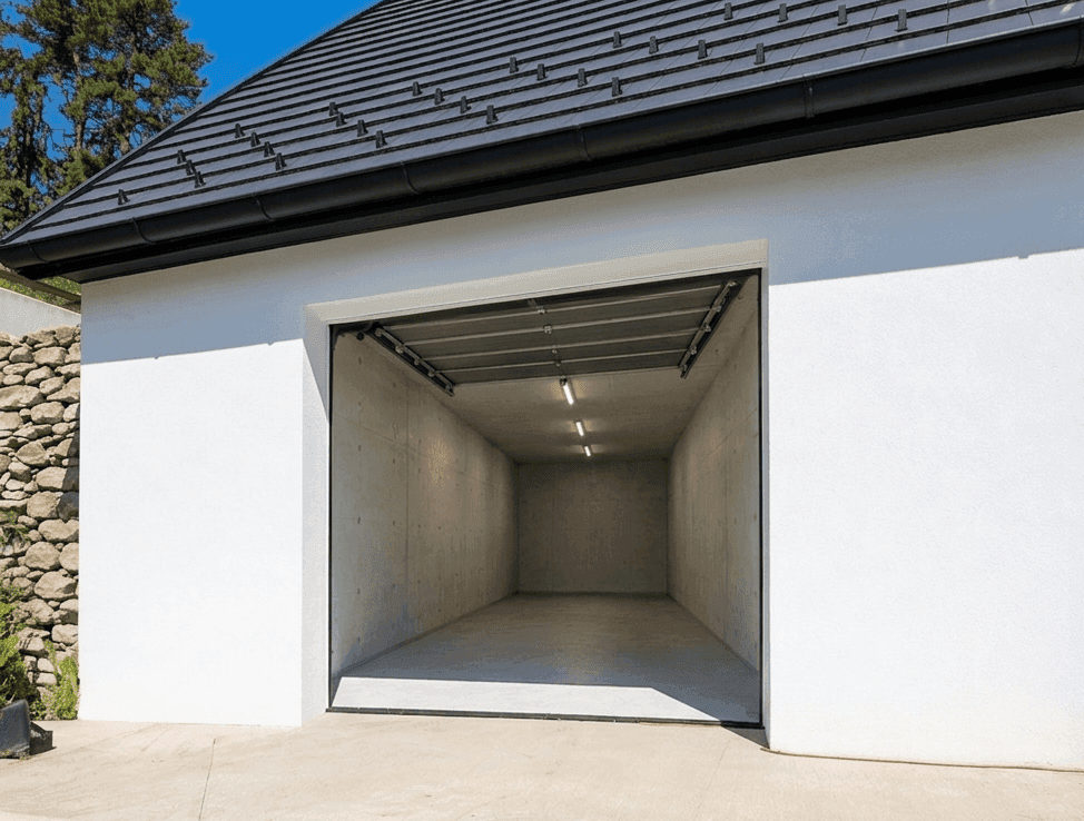 Einzelgarage mit offenem Tor, Betonwänden und Deckenbeleuchtung unter einem dunklen Ziegeldach.
