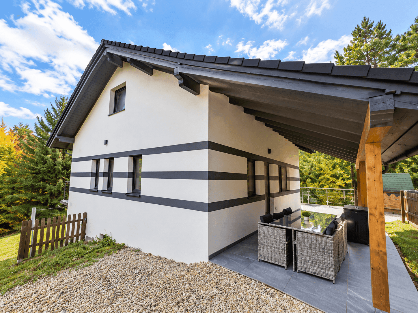 Überdachte Terrasse mit Outdoor-Möbeln und Blick auf die umliegende Natur.