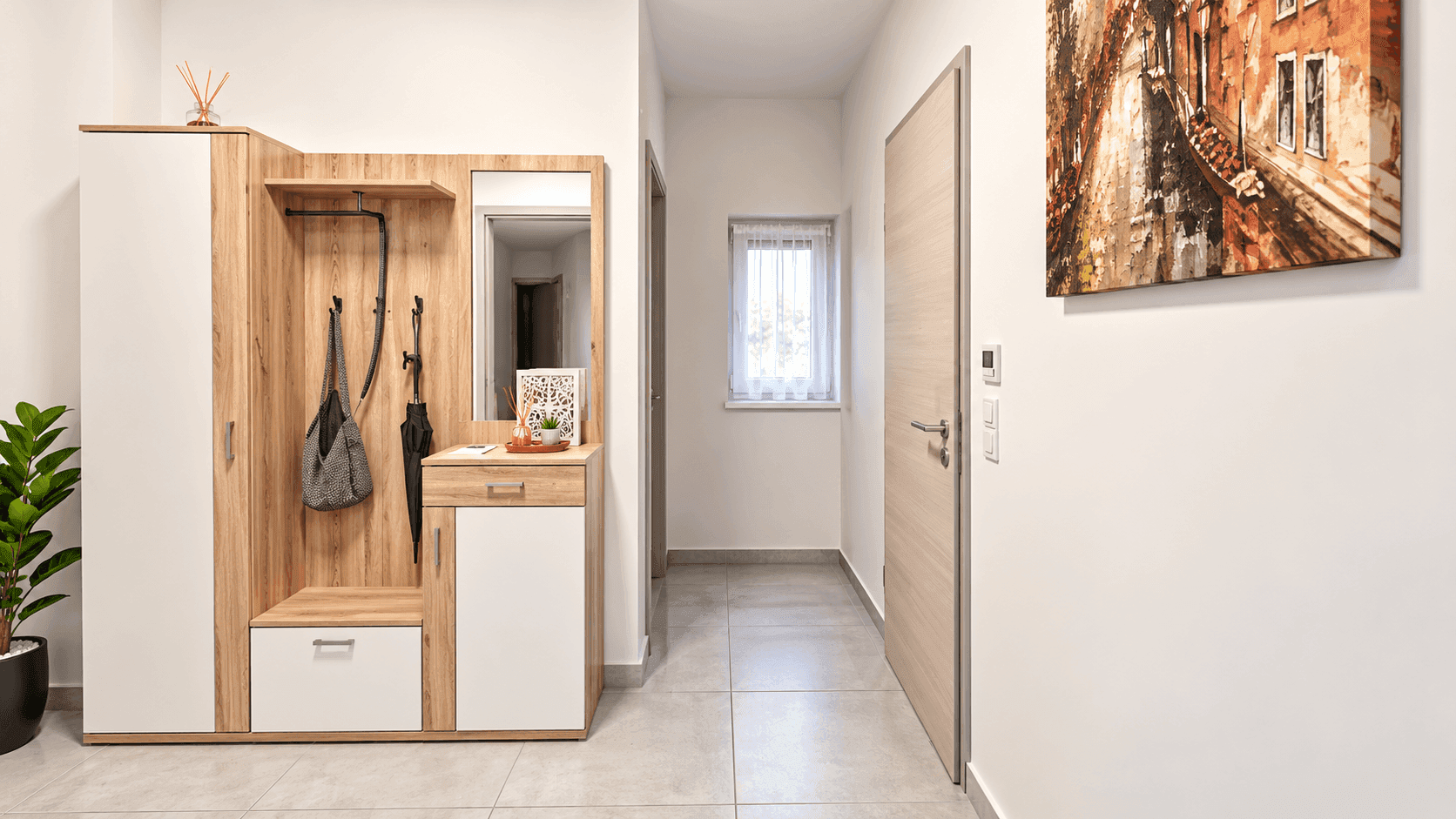 Heller Eingangsbereich mit Garderobe, Spiegel und Fliesenboden.