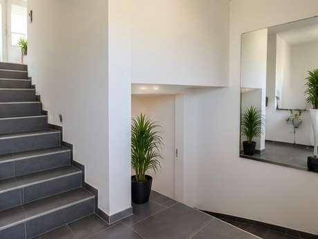 Moderner Eingangsbereich mit gefliester Treppe und großem Spiegel.