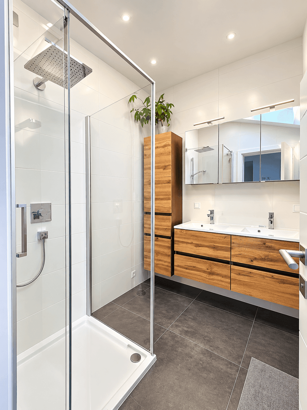 Modernes Badezimmer mit großer Glasdusche, Doppelwaschbecken und Holzschränken.
