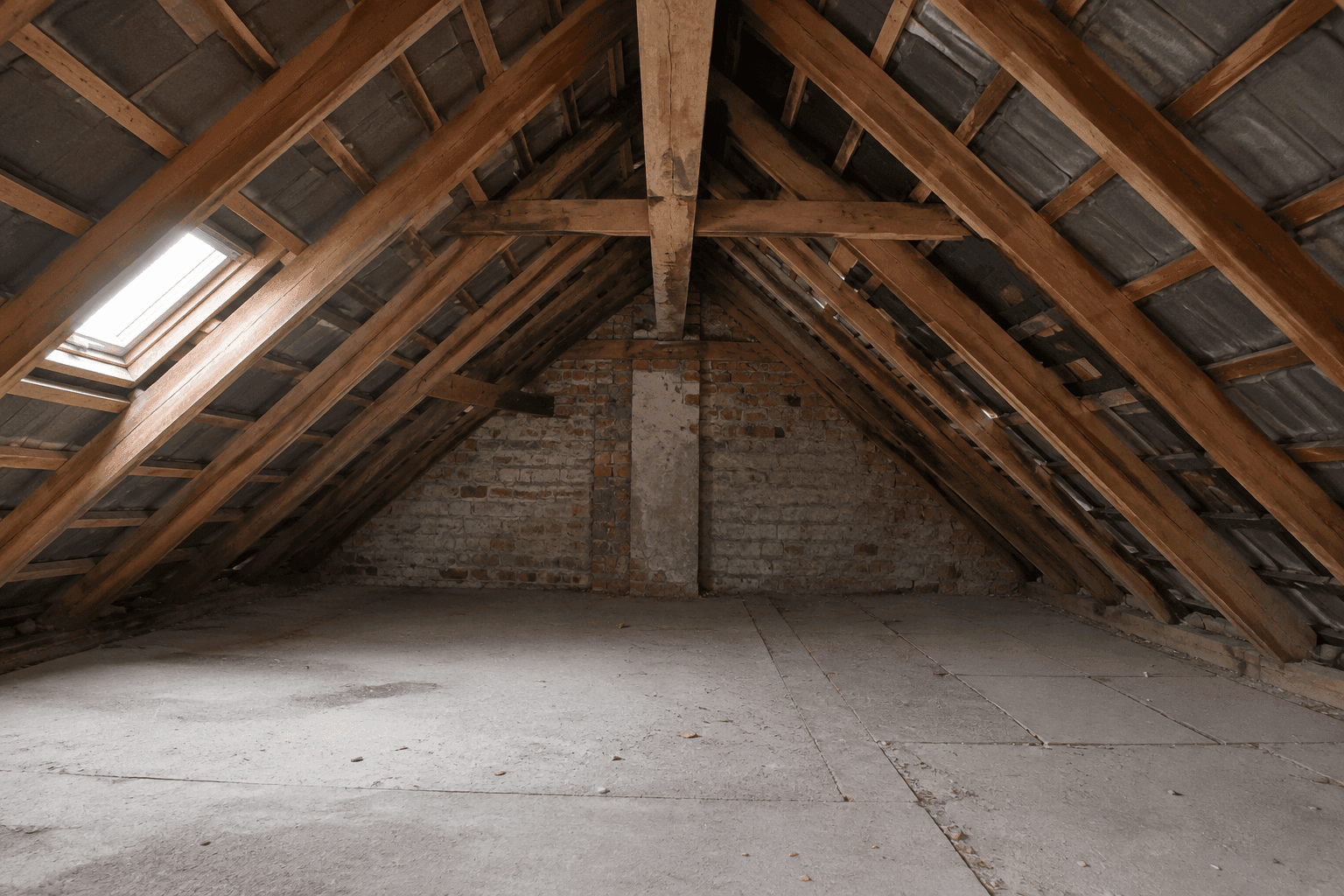 Unausgebauter Dachboden mit sichtbarer Holzkonstruktion und einem einzelnen Dachfenster, bereit für die Umgestaltung.