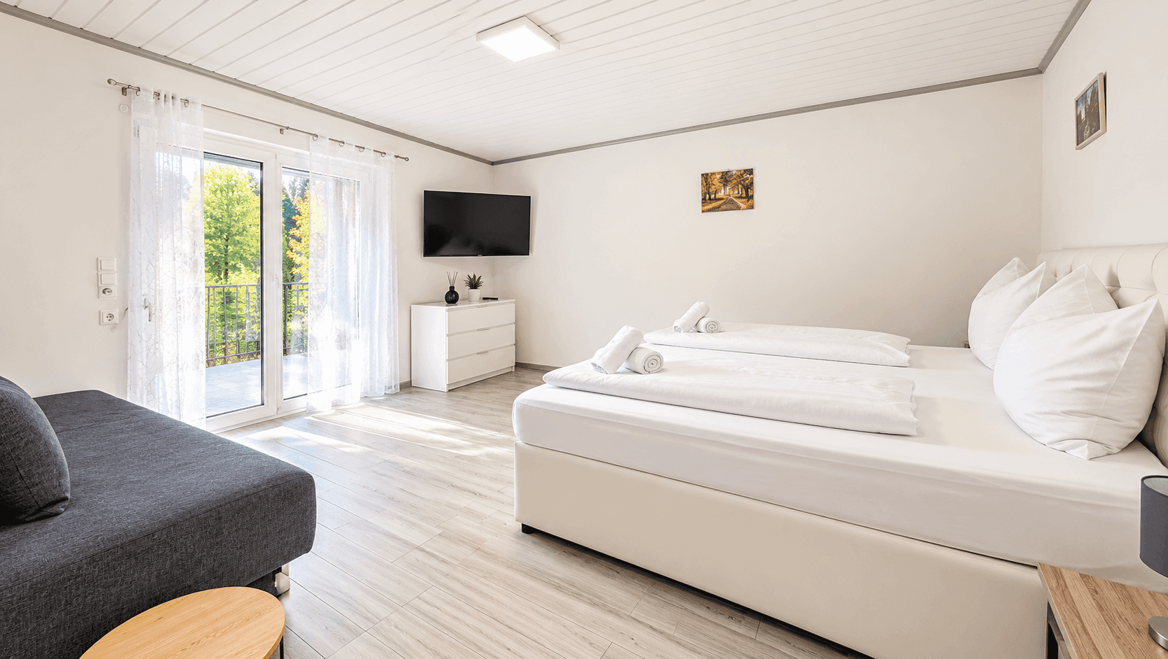 Geräumiges Schlafzimmer mit Doppelbett, Sofa und Zugang zu einem Balkon.