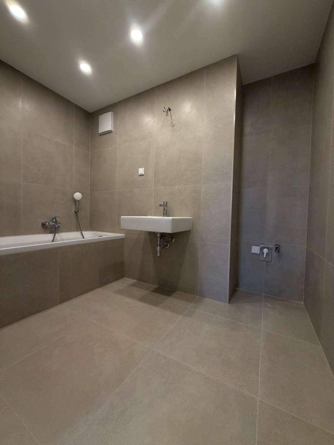 Geräumiges Badezimmer mit Badewanne, Waschbecken und modernen Fliesen.