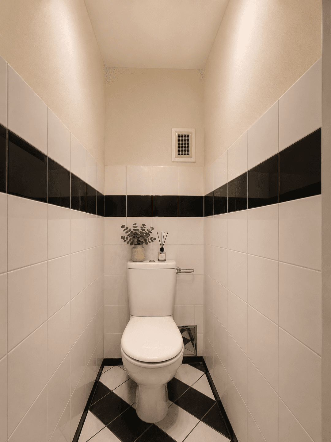 Kleines WC mit Toilette, schwarz-weißen Fliesen und einem Schachbrettmuster auf dem Boden.