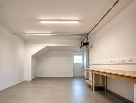 Geräumige Garage mit Werkbank und Fenster, ideal für Hobby und Lagerung.