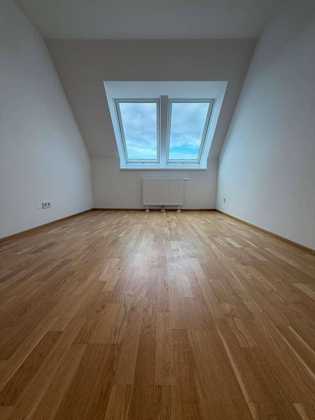 Heller Raum mit Dachfenstern und Holzboden, ideal für Schlafzimmer oder Büro.