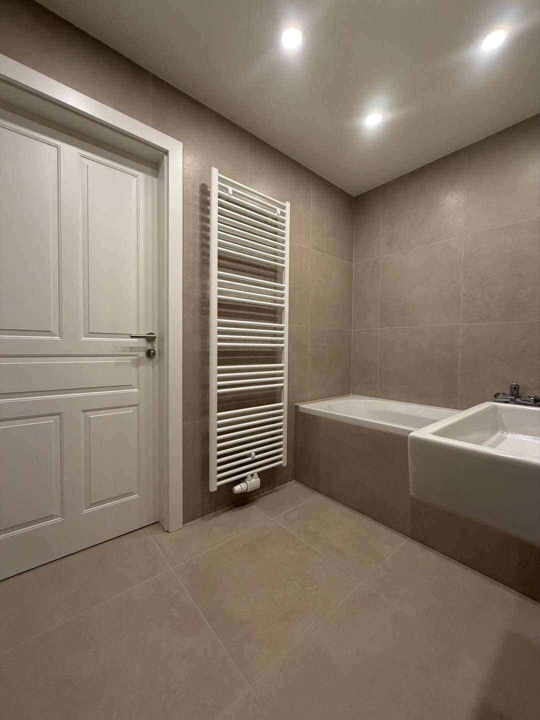 Modernes Badezimmer mit Badewanne, Waschbecken und beheiztem Handtuchhalter.