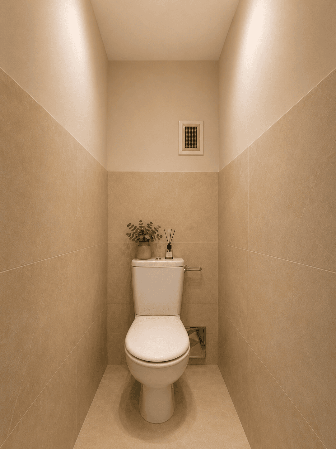 Kleines WC mit Toilette und beigefarbenen Fliesen an den Wänden.