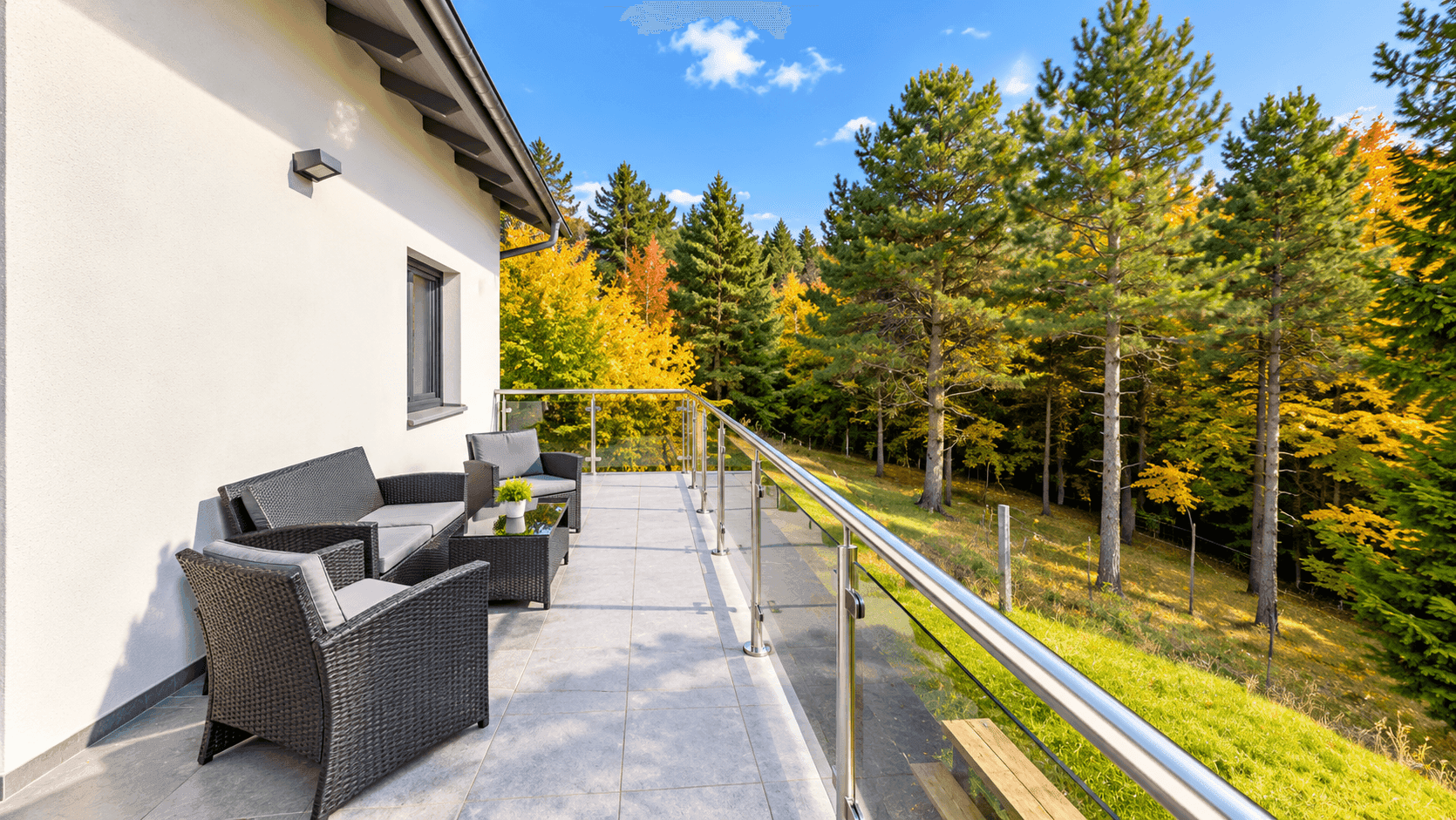 Geräumiger Balkon mit modernen Outdoor-Möbeln und weitem Blick auf den Wald.
