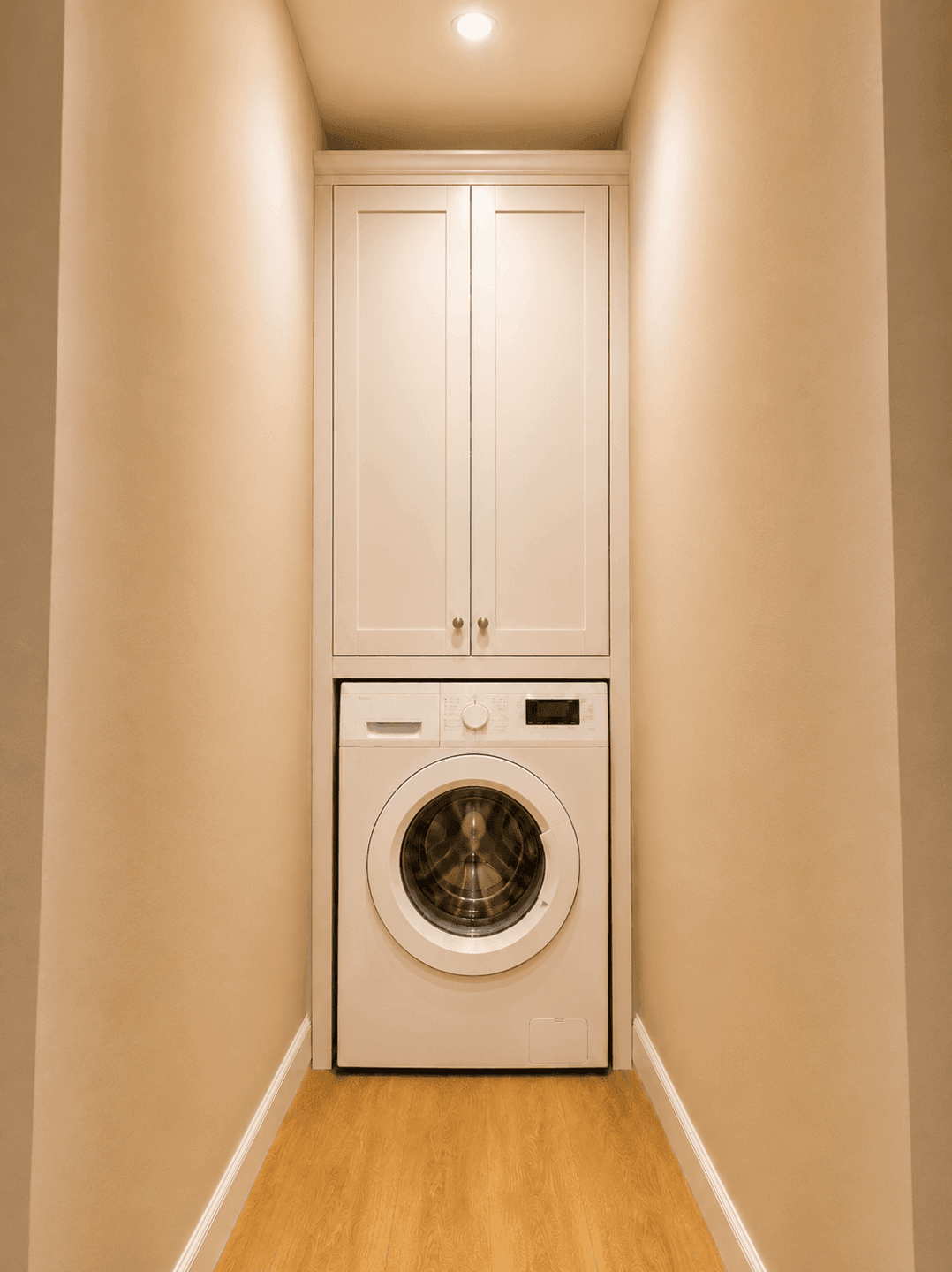 Schmaler Hauswirtschaftsraum mit Waschmaschine und praktischem Wandschrank.