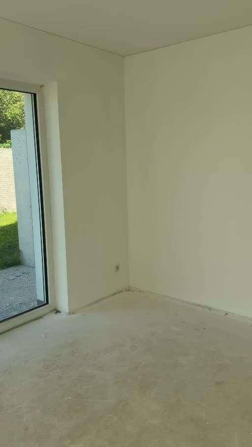 Leerer Raum im Rohbau mit Zugang zum Außenbereich, bereit für den Innenausbau.