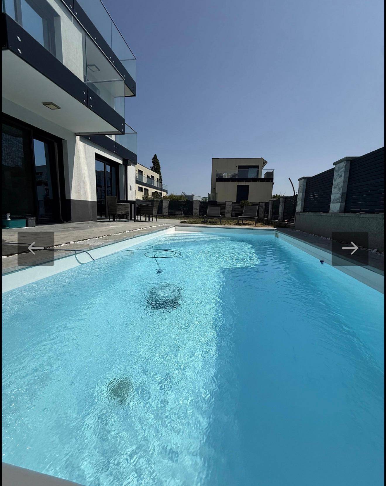 Moderner Außenbereich mit großem Swimmingpool, Terrasse und zeitgenössischer Architektur.