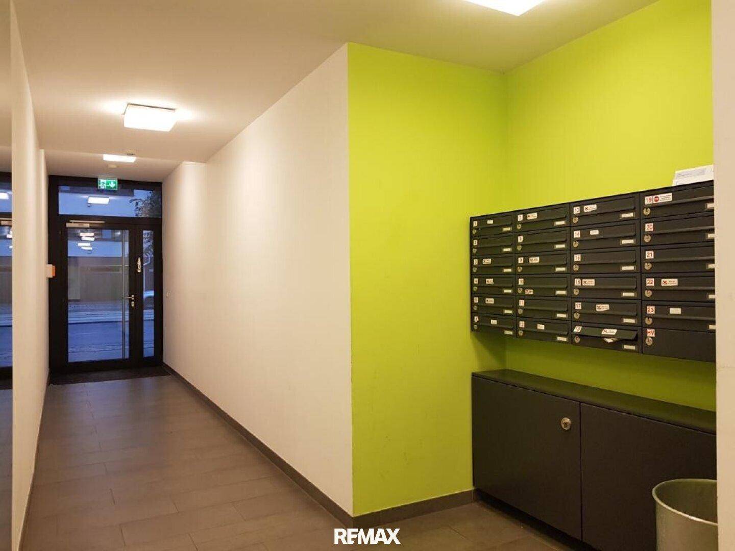 Eingangsbereich des Gebäudes mit Briefkästen und einer auffälligen grünen Akzentwand.