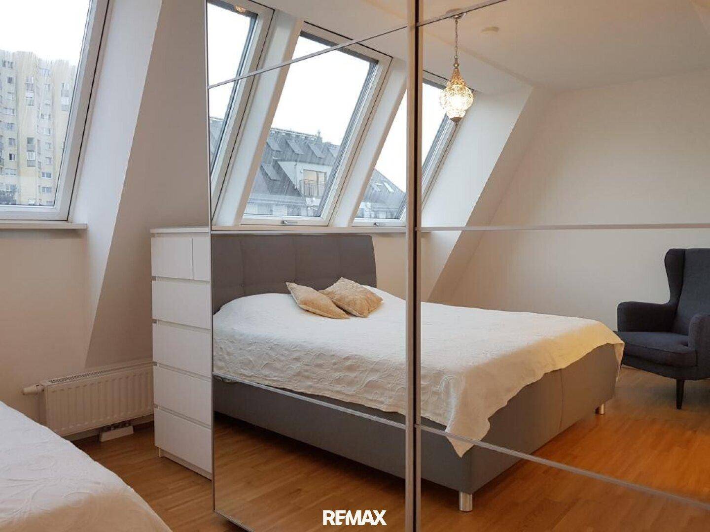 Helles Schlafzimmer mit Doppelbett, Kommode und großen Dachfenstern für viel Licht.