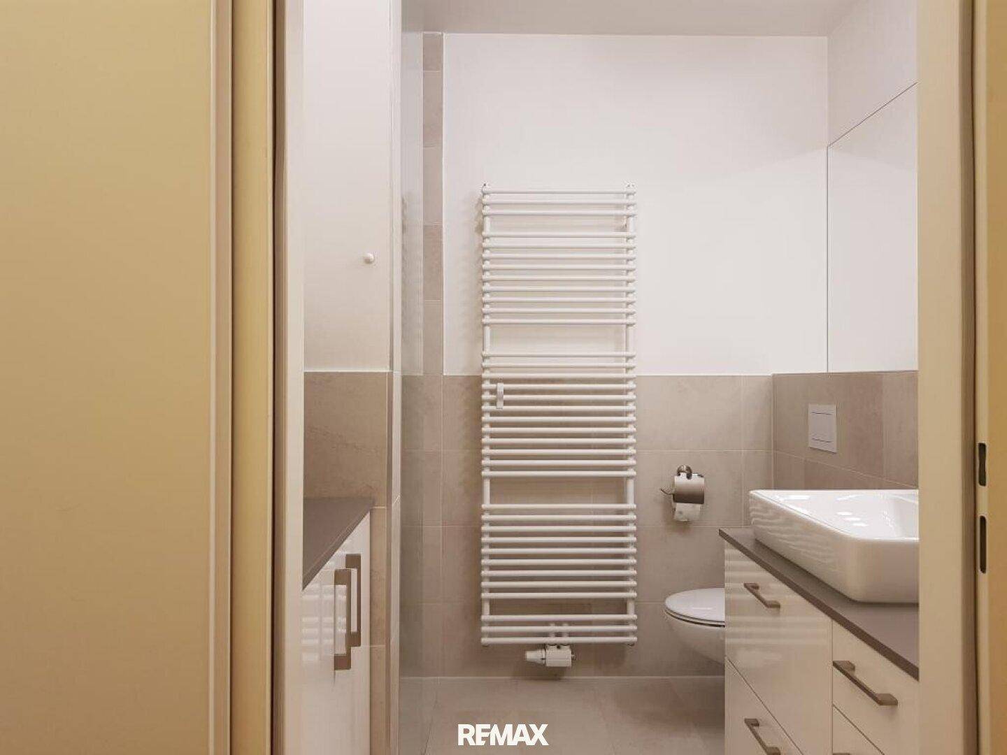 Funktionales Badezimmer mit Waschtisch, WC und beheiztem Handtuchhalter in neutralen Farbtönen.