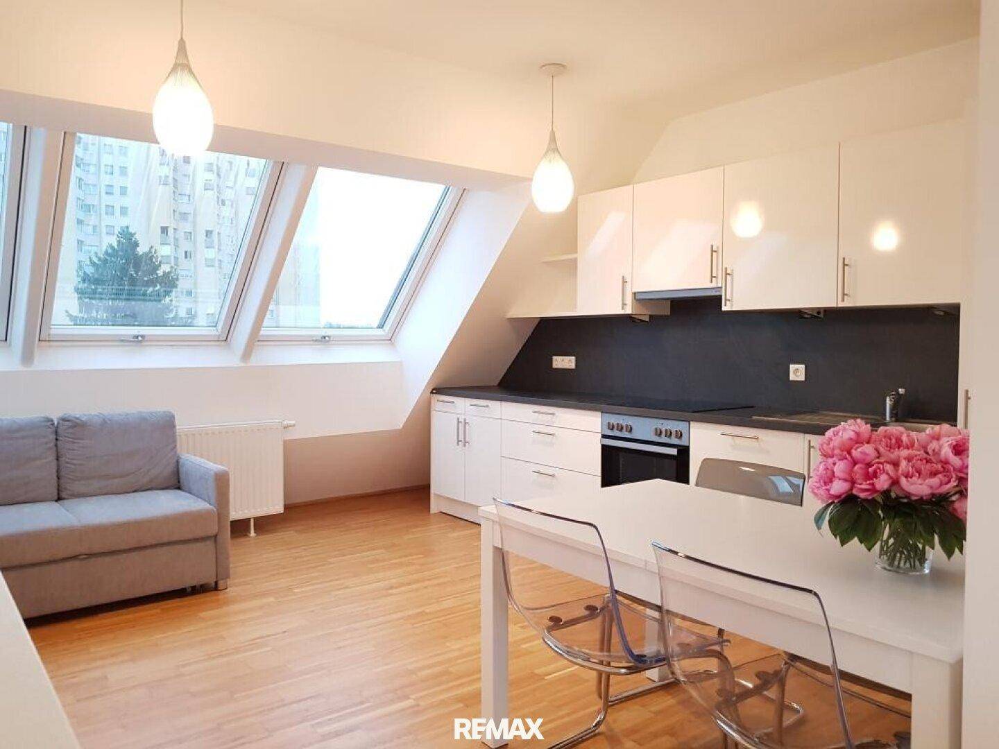Offener Wohn- und Essbereich mit integrierter Küche, bequemer Couch und großen Dachfenstern.