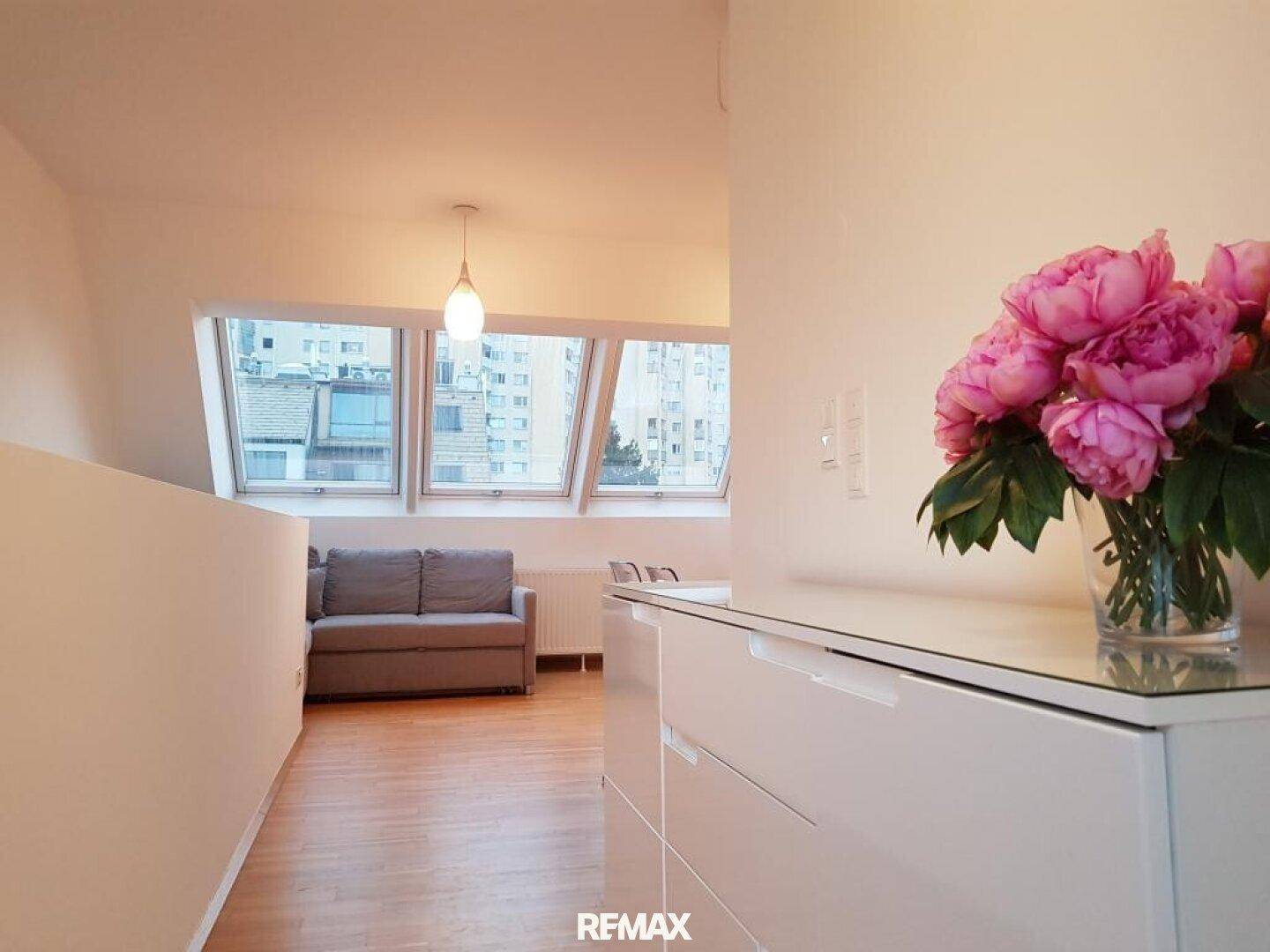 Gemütlicher Wohnbereich mit Sofa, Kommode und großen Dachfenstern für viel Tageslicht.